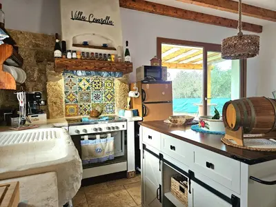 a kitchen with a stove and a refrigerator at Villa Cerasella - Rustic Sicilian Retreat with Private Pool & Sunset View in Trappeto