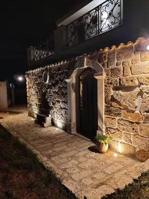 a stone building with a black door and a balcony at Villa Cerasella - Rustic Sicilian Retreat with Private Pool & Sunset View in Trappeto