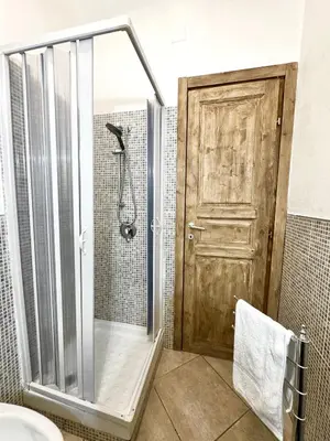 a shower with a wooden door in a bathroom at Family house in Palermo
