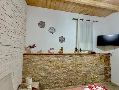 a living room with a brick wall and a flat screen tv at Family house in Palermo