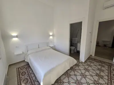 a white bedroom with a bed and a bathroom at GiuAdel casa Palermo in Palermo