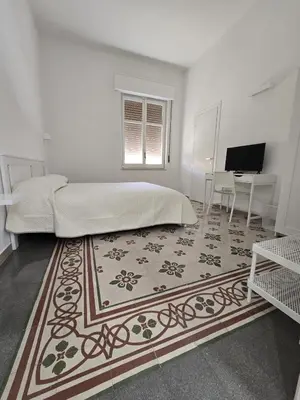 a white bedroom with a bed and a desk at GiuAdel casa Palermo in Palermo