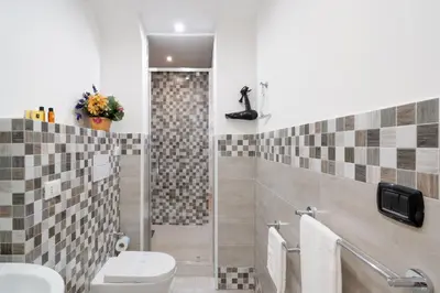 a bathroom with a toilet and a shower with tiles at ControCanto Elegant Stay - 3 bedroom flat in Palermo