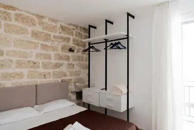 a bedroom with a stone wall with a bed and a mirror at Cielo D'Alcamo Palazzo Oliva in Alcamo