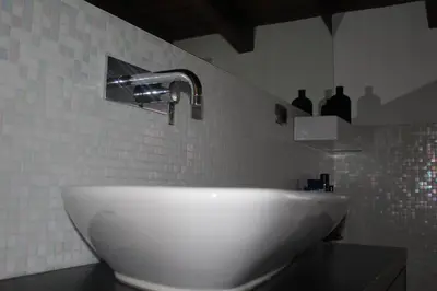 a white sink in a bathroom with bottles on the wall at Imbriani103 in Cinisi