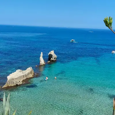 two people swimming in the water near some rocks at La Finestra Sul Tirreno in Terrasini