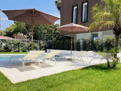 a group of chairs and umbrellas next to a pool at Design Villa with private pool in Carini