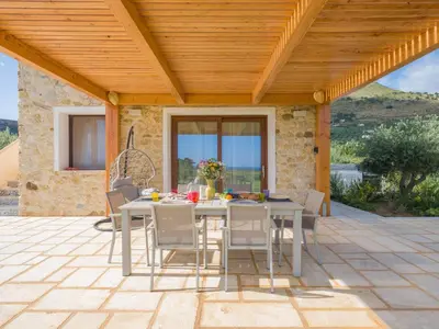 a patio with a table and chairs under a wooden roof at Villa Aura Scopello in Castellammare del Golfo