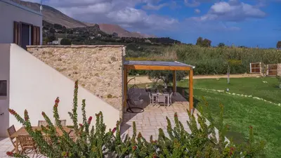 a patio with a table and chairs and a stone wall at Villa Aura Scopello in Castellammare del Golfo