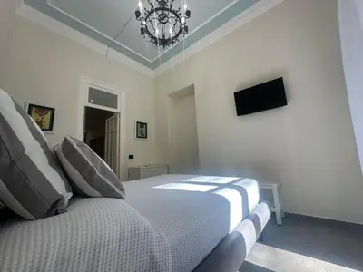 a white bedroom with a bed and a chandelier at Granatelli Apartment in Palermo