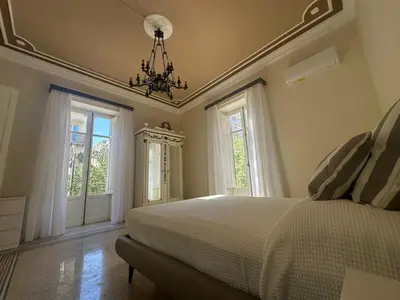 a bedroom with a bed and windows and a chandelier at Granatelli Apartment in Palermo