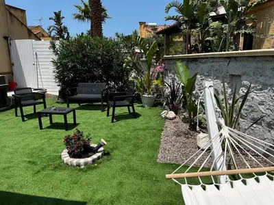a backyard with green grass and chairs and a hammock at Villa Vulcano - Le Ville del Mediterraneo in Campofelice di Roccella