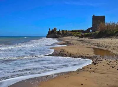 a beach with a castle in the distance at Villa Vulcano - Le Ville del Mediterraneo in Campofelice di Roccella
