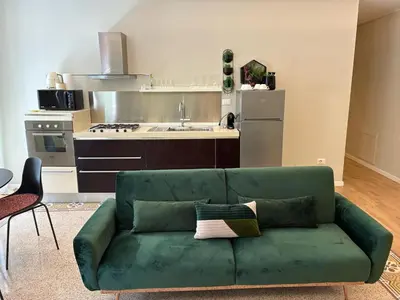 a living room with a green couch in front of a kitchen at Vista Cattedrale - City Center in Palermo