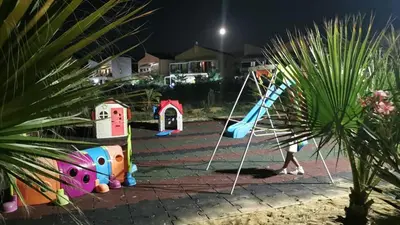 a child walking past a playground at night at Pine Beach House - Villaggio Turistico con Piscina e Animazione in Campofelice di Roccella