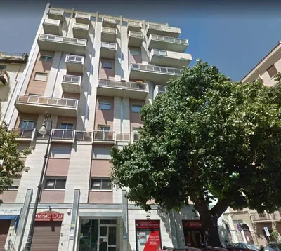 a tall building with a tree in front of it at Central Apartment Cavour in Palermo