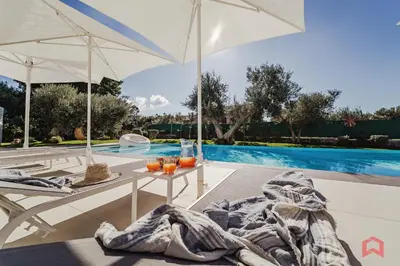 a patio with a table and umbrella next to a swimming pool at Strepitosa Villa Vista Mare con Piscina Privata in Terrasini