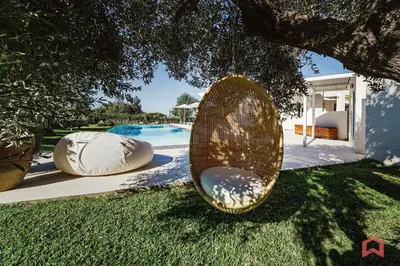 a wicker object sitting in the grass next to a pool at Strepitosa Villa Vista Mare con Piscina Privata in Terrasini