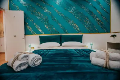 a bedroom with a blue bed with a green wall at Cama Luxury Rooms in Palermo