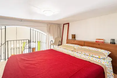 a bedroom with a red bed with a red blanket at La petite Bastet in Palermo