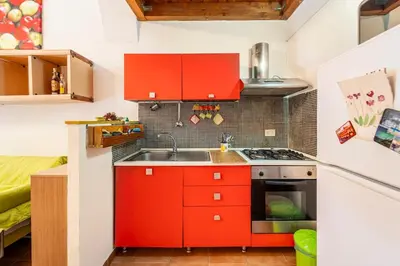 a small kitchen with red cabinets and a sink at La petite Bastet in Palermo