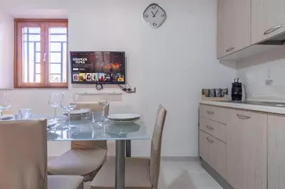 a kitchen with a table with chairs and a clock on the wall at 15 min to Historic Center, 5 min to Bus, Balcony in Palermo