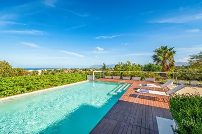 a swimming pool with chairs and the ocean in the background at Villa Ametista in Alcamo
