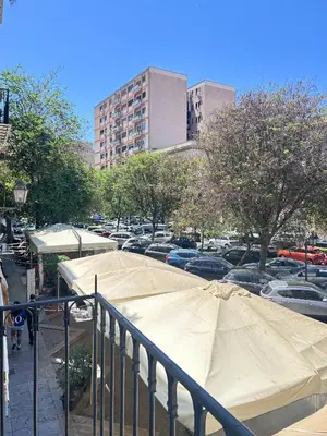 a large tan umbrella in a parking lot with cars at Dimora dell'Olivella 1 in Palermo