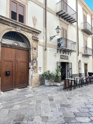 a building with a wooden door and tables and chairs at Dimora dell'Olivella 1 in Palermo