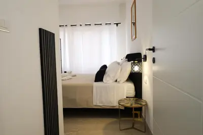 a bedroom with a bed with white sheets and a window at Tolo Tolo Apartaments in Palermo