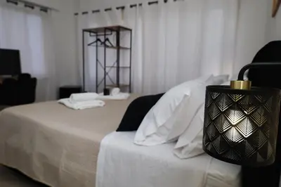 a white bed with a black lamp on top of it at Tolo Tolo Apartaments in Palermo