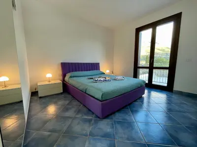a bedroom with a purple bed and a large window at Casa Sterlizia by Holiday World in San Vito lo Capo