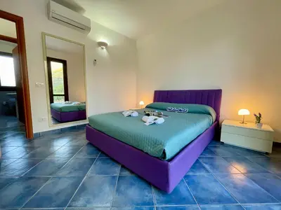 a bedroom with a purple bed in a room at Casa Sterlizia by Holiday World in San Vito lo Capo