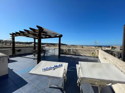 a patio with two white chairs and a pavilion at Casa Sterlizia by Holiday World in San Vito lo Capo