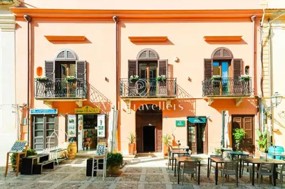 a building with tables and chairs in front of it at Elegante palazzo storico con splendida vista mare in Castellammare del Golfo