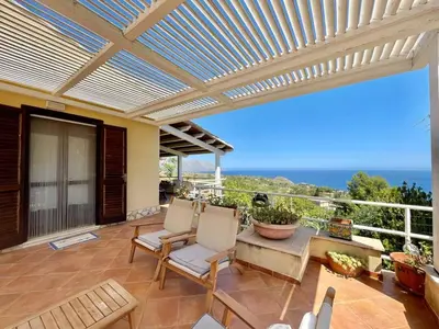 a patio with a pergola and chairs and the ocean at Villa Dorotea in Castellammare del Golfo