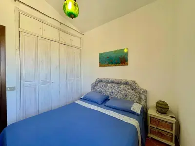 a bedroom with a blue bed and a painting on the wall at Villa Dorotea in Castellammare del Golfo