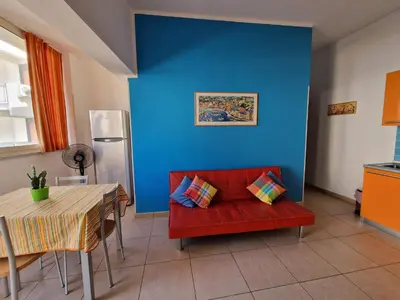 a living room with a red couch and a blue wall at Case d'estate Mondello in Palermo