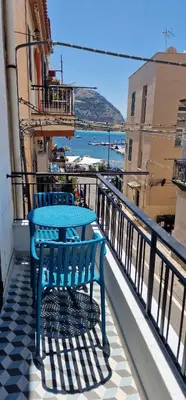 a blue bench sitting on a balcony looking out at the water at Casa Fortuna Mondello in Palermo