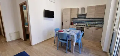a small kitchen with a table and blue chairs at Casa Fortuna Mondello in Palermo