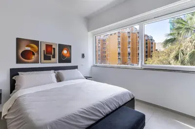 a white bedroom with a large bed and a window at Case libertà in Palermo