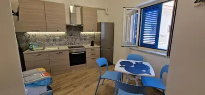 a kitchen with a table and blue chairs in it at Casa Elisa in Palermo