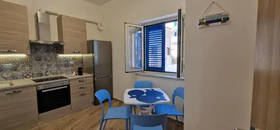 a kitchen with blue chairs and a table and a window at Casa Elisa in Palermo