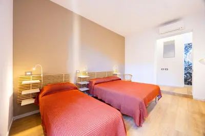 two beds in a room with orange sheets at Rosalia e le altre in Palermo