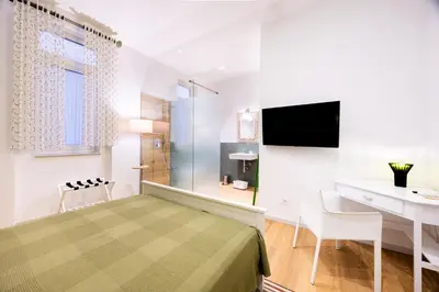 a bedroom with a bed and a desk and a television at Rosalia e le altre in Palermo