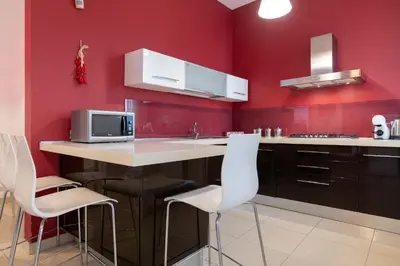 a kitchen with red walls and a table with white chairs at GuestHost - Palermo Roomy and Modern Apartment in Palermo