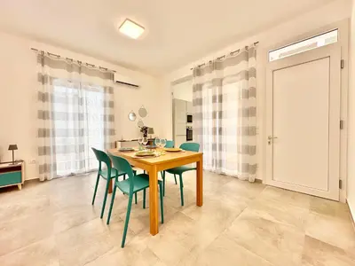 a dining room with a wooden table and green chairs at Zàgave Apartment a 200 mt dal mare in Alcamo