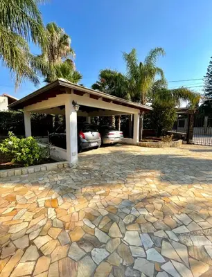 a driveway with a fence and palm trees at Villa Seaside in Cinisi