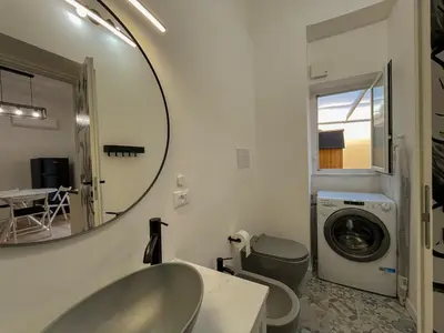 a bathroom with a sink and a mirror and a washing machine at Oasi urbana Palermo in Palermo