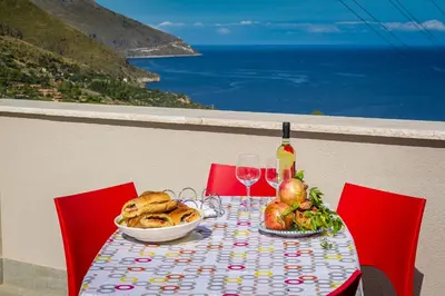 a table with a plate of food and wine glasses at APT NINO in Villa Rosaria Vista Mare Zingaro in Scopello